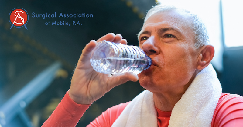 Older Man In Red Shirt with White Towel Around His Neck Drinking Bottled Water