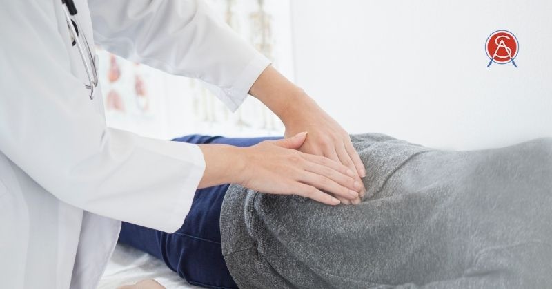 Woman with abdominal pain lays on exam table for doctor to evaluate her stomach pain at Surgical Association of Mobile