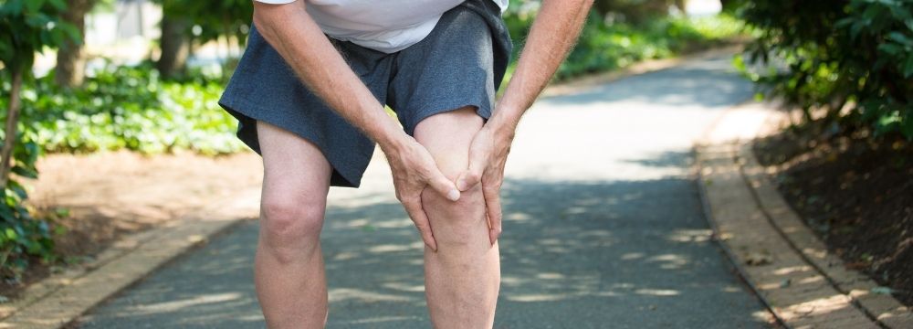 Man has knee pain walking on concrete surface as he exercises for weight loss after bariatric surgery 