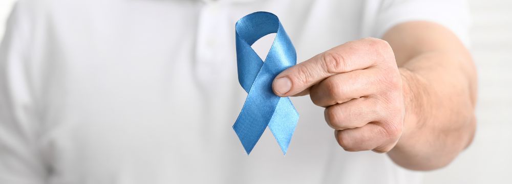 Colorectal cancer survivor holds blue ribbon celebrating new research toward cure for cancer 