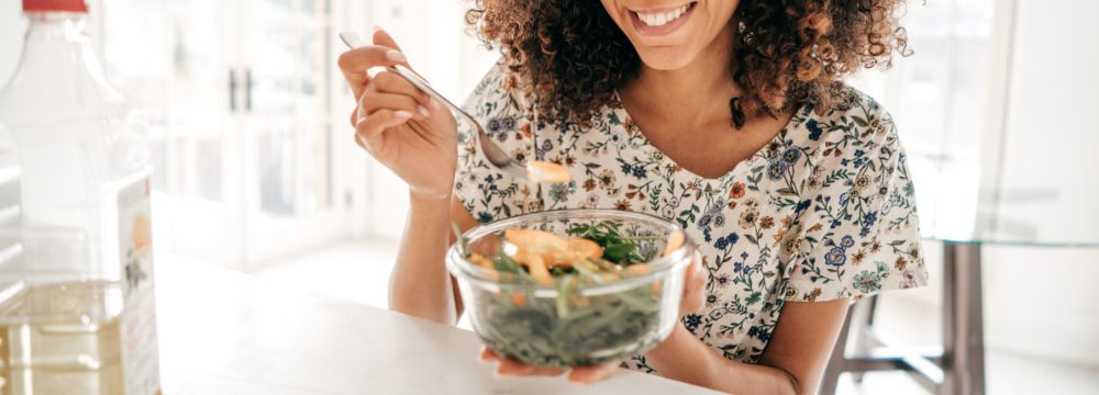 woman eating salad with bottle of water next to her