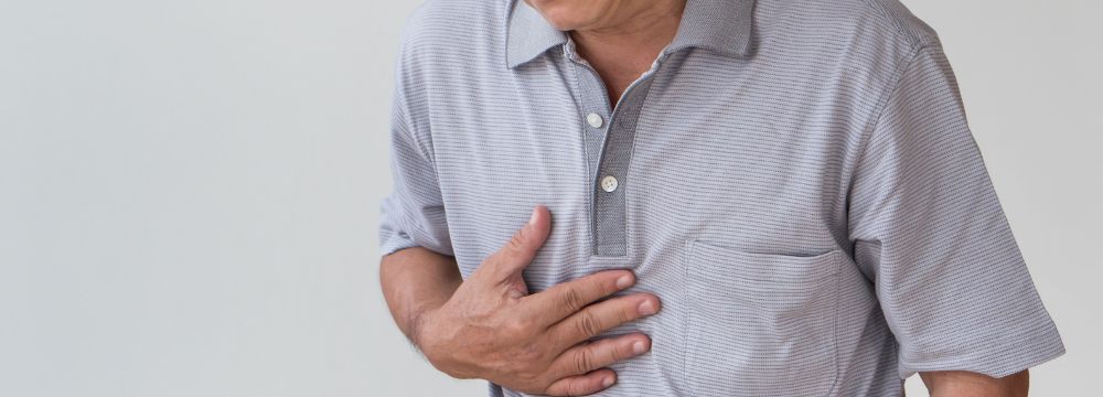 Man with GERD holding chest in pain