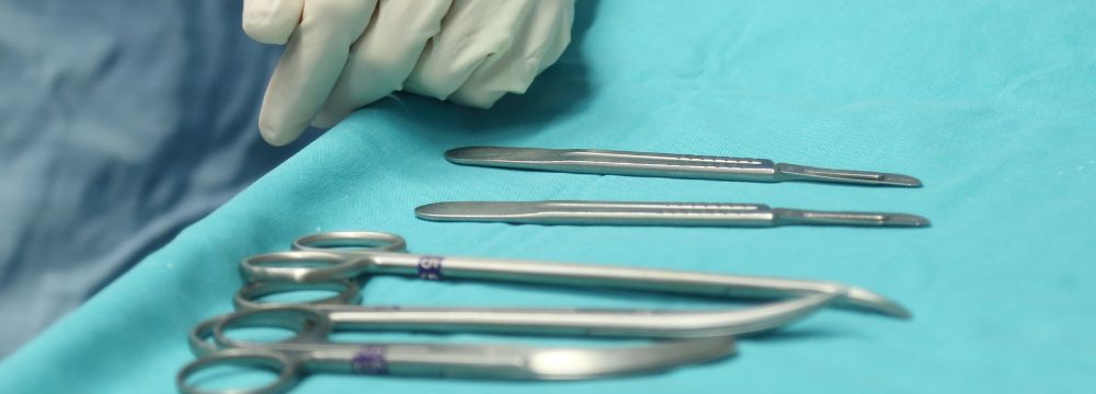 Array of surgical instruments scattered on tray with surgeon's white glove