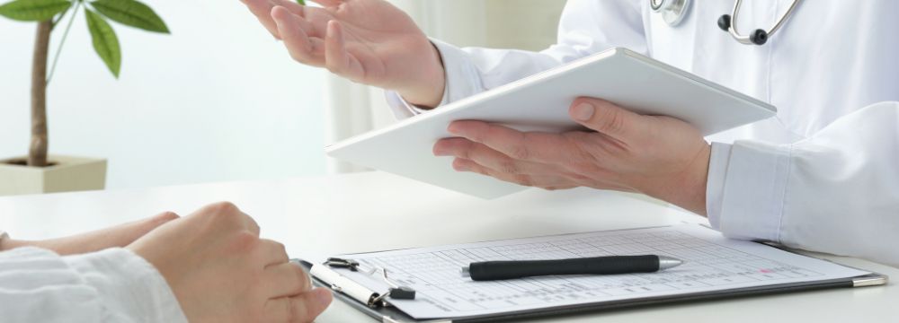 Male doctor with paper consulting with a patient with clipboard, paper and pen on table