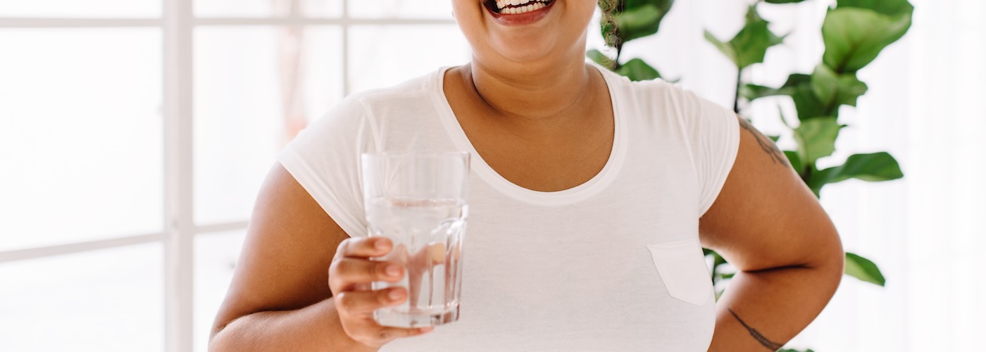 Woman holding glass of water and smiling 