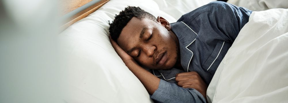 Man sleeping in bed with hand on head